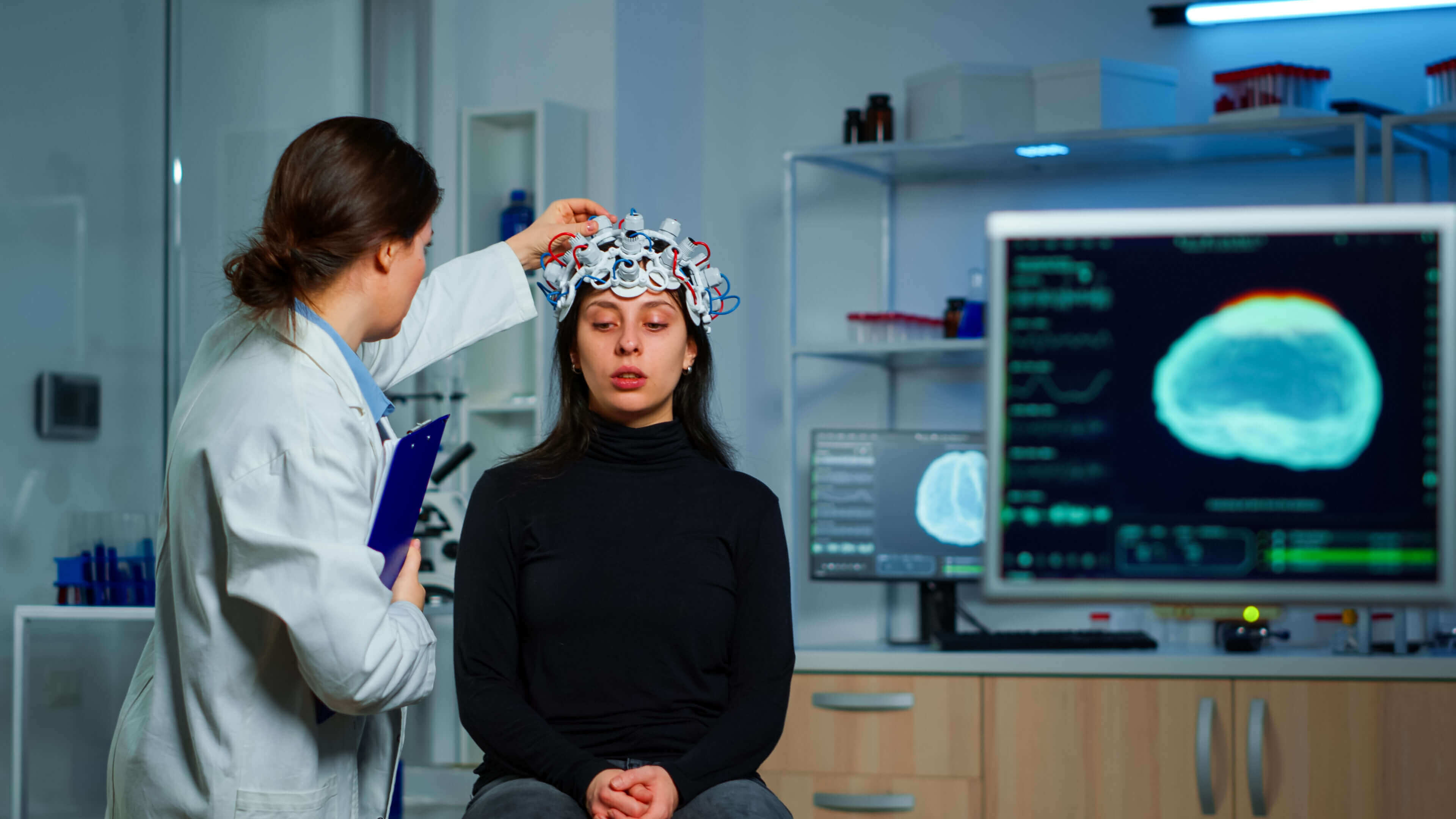 Scientist fitting EEG cap on woman in lab.