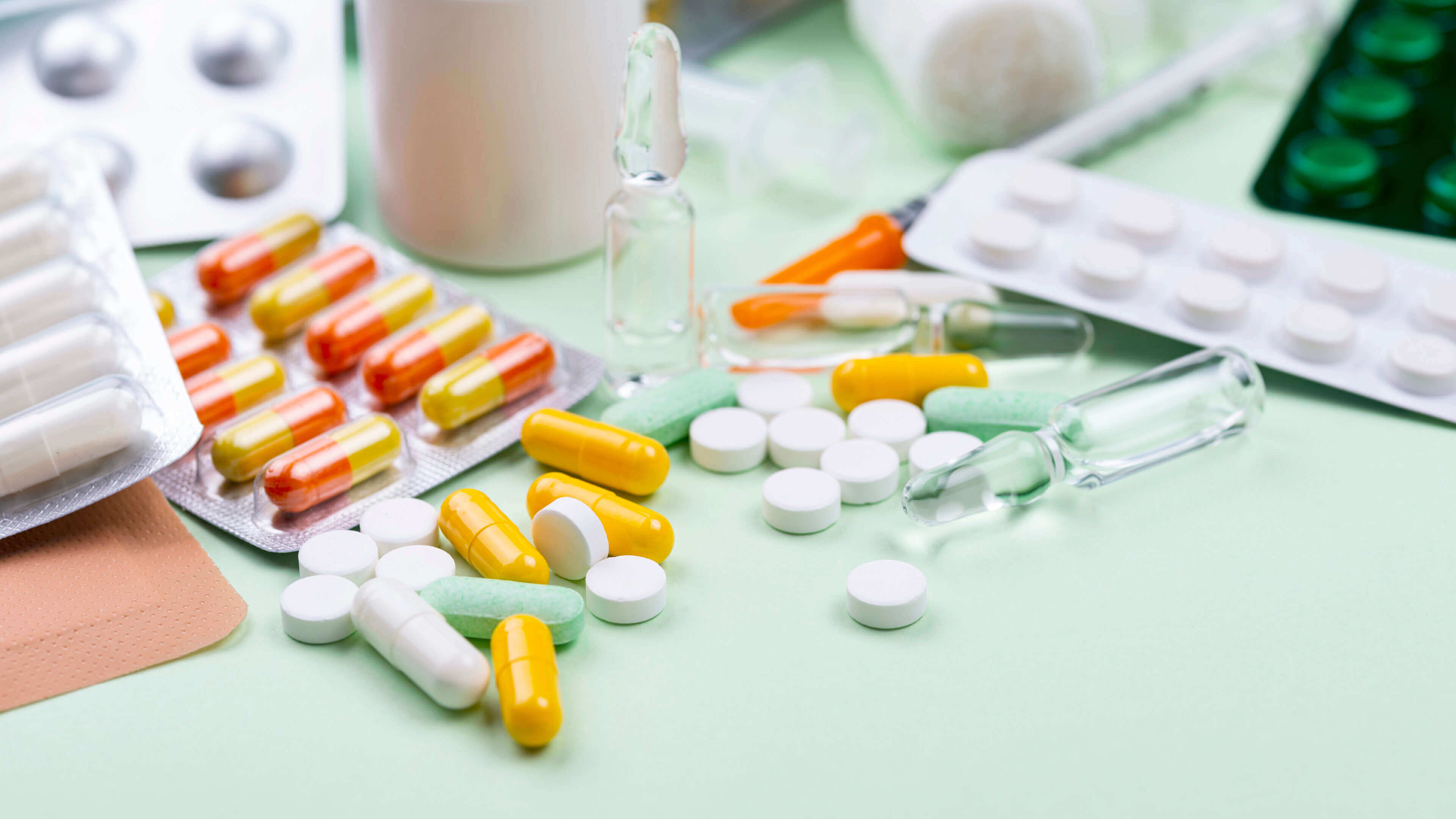 Various pills and capsules scattered on a table with medical tools.
