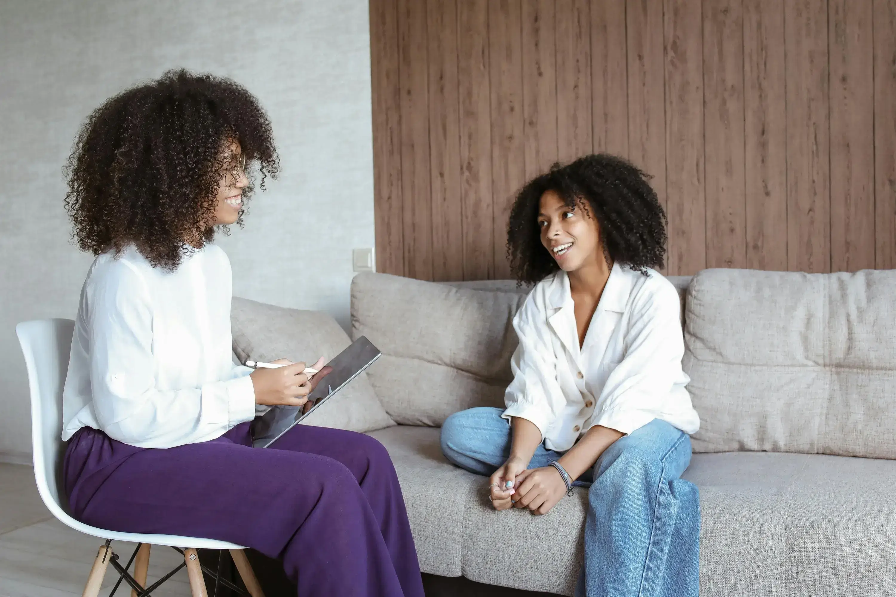 Two women engaged in a warm conversation on a couch.