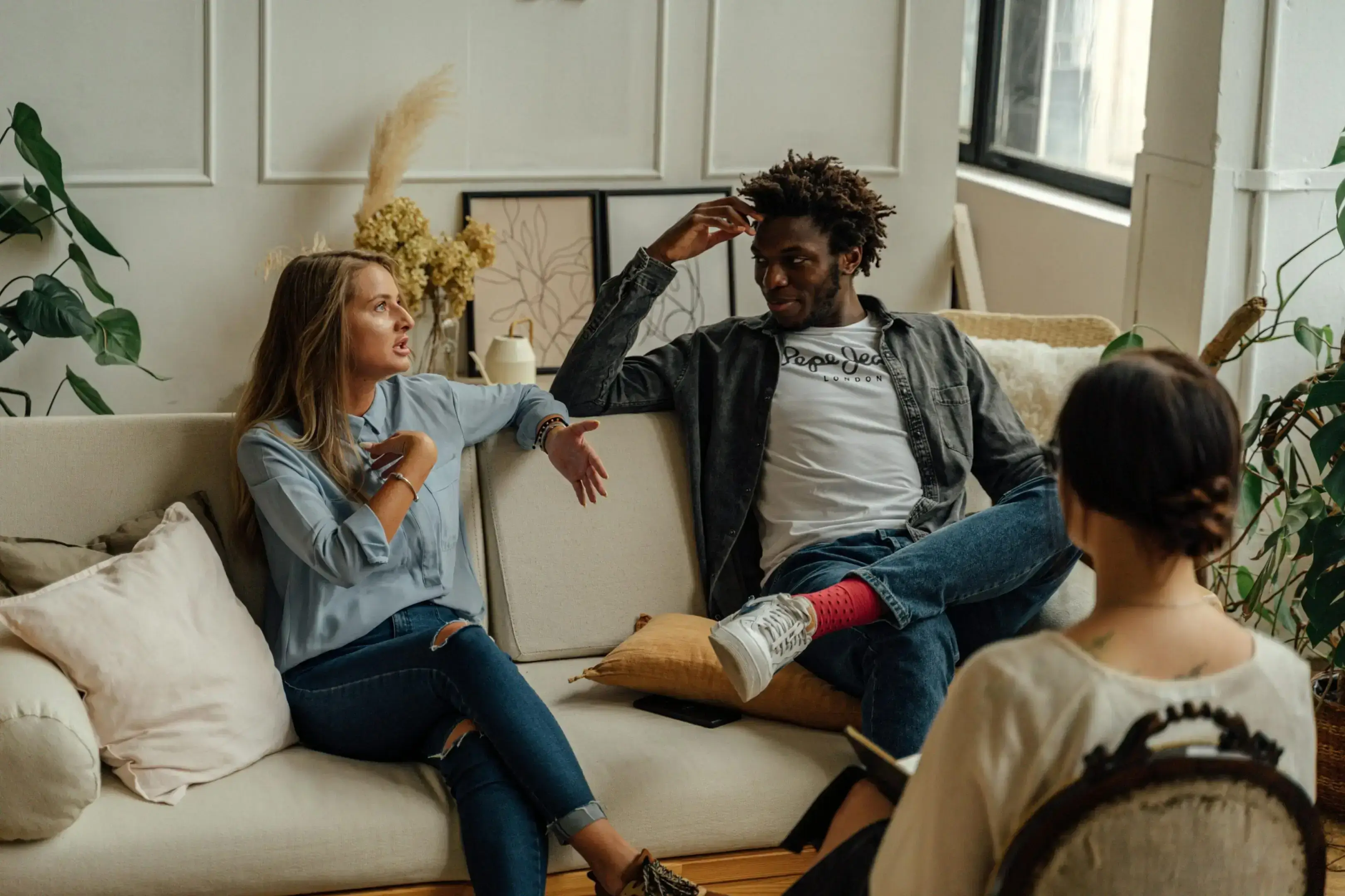 Three friends chatting and relaxing on a sofa in a cozy living room.